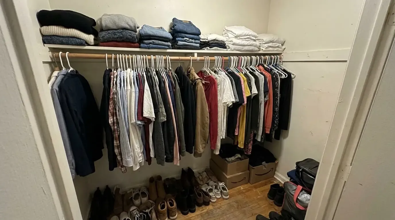 Clean white closet with hanging fabric organizer and clothes on rod